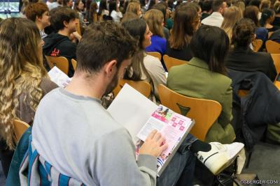 Un étudiant lit une plaquette pendant les échanges - Agrandir l'image 4 sur 5, fenêtre modale