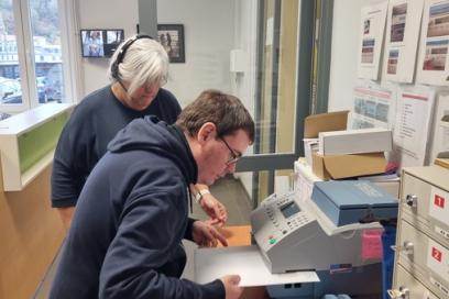 Une femme aidant un homme en situation de handicap à photocopier des documents - Agrandir l'image, fenêtre modale